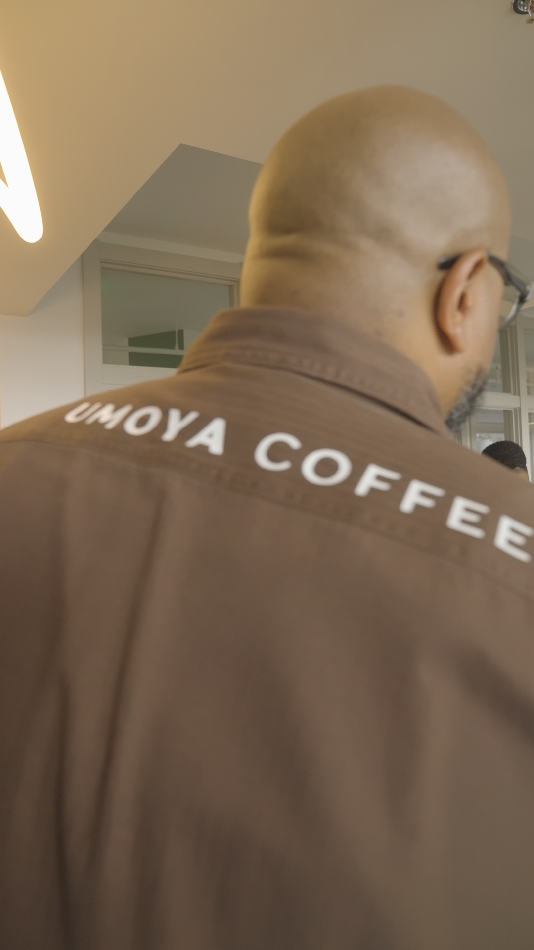 A UMOYA COFFEE team member seen from behind, wearing a branded jacket, at the Illumination Summer Solstice gathering.